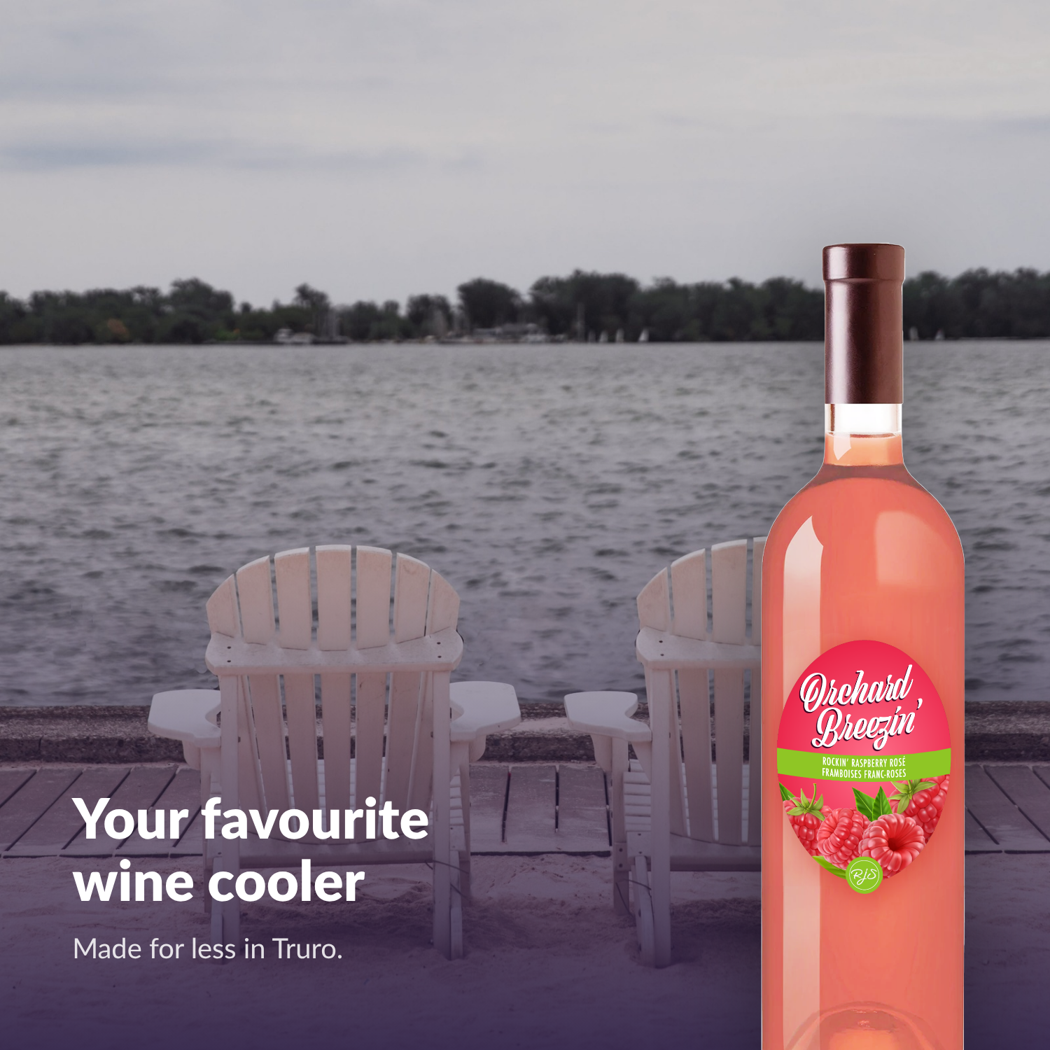 Orchard Breezin' Rockin' Raspberry Rosé bottle by lakeside chairs at the shore