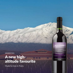 Bottle of Altitude Red in front of a Mendoza winery and the snow-capped Andes